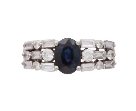 A sapphire and diamond dress ring in white gold, the central oval cut blue sapphire weighing approximately 1.15cts flanked by