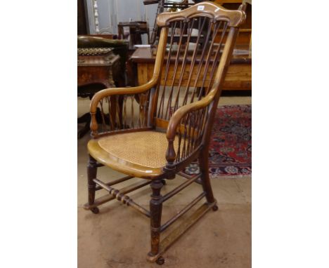 A 1920s cane-seated and stick-back elbow chair, with sled caster base 