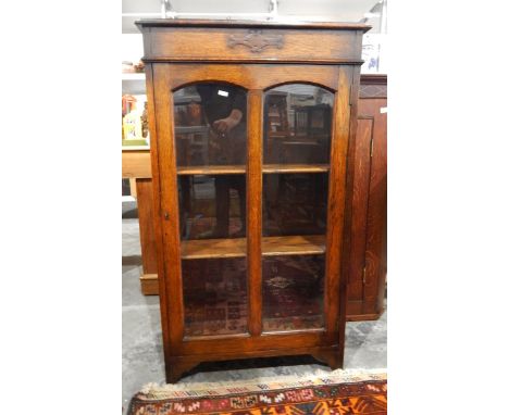 Oak glazed bookcase with panelled door enclosing shelves, on bracket feet, width 61cm 