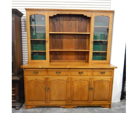 Pale oak kitchen dresser, the rack with a pair of glazed cupboards and two central open shelves, four short frieze drawers be