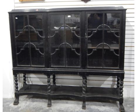 Jacobean-style ebonised glazed bookcase, the three glazed doors enclosing shelves, raised on turned spiral supports with open