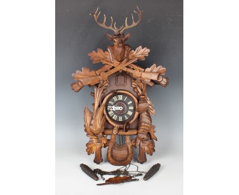 A 20th century Swiss carved softwood cuckoo clock with weight driven movement, the case carved with stag head surmount above 