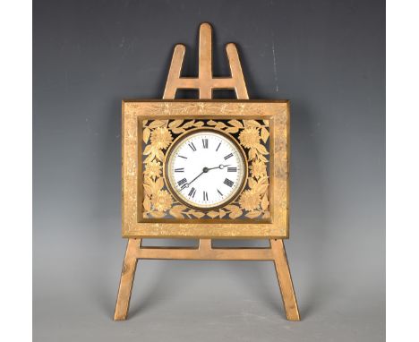 A late Victorian gilt brass novelty timepiece in the form of an artist's easel, the rectangular frame engraved with flowers a