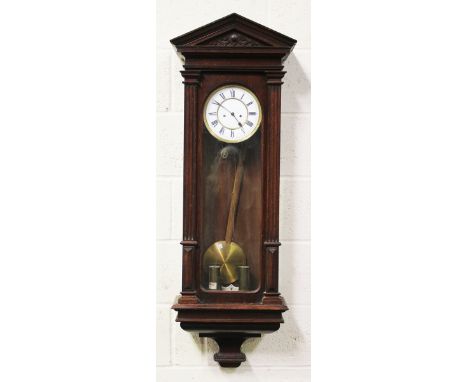 A late 19th century oak Vienna style wall clock with eight day movement striking on a gong, the two piece enamel dial with Ro