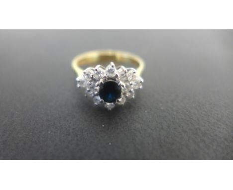 An 18ct gold diamond and sapphire ring set with an oval sapphire approx 5mm x 4mm - surrounded by 14 small white diamonds - r