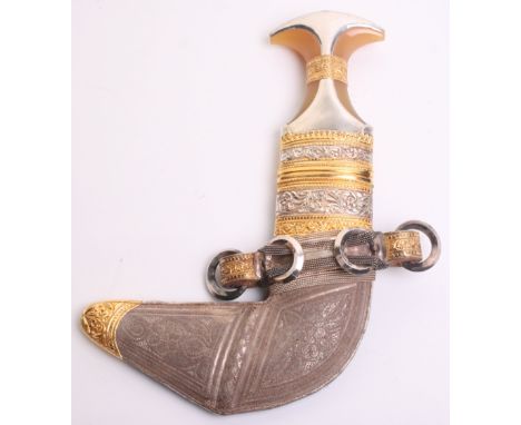 Good Quality Saudi Dagger Jambya, polished blade with central rib, silver and gilt mounts to hilt and sheath, embossed with f