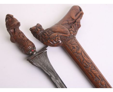 A Madura Kris, straight blade 31cms etched with black and silver coloured pamor, carved wooden hilt incorporating a Dutch hel