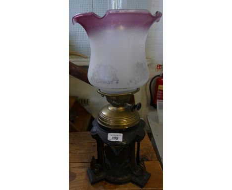 An unusual early 20th Century oil lamp, cast metal foliate base, brass font, and frosted glass shade.