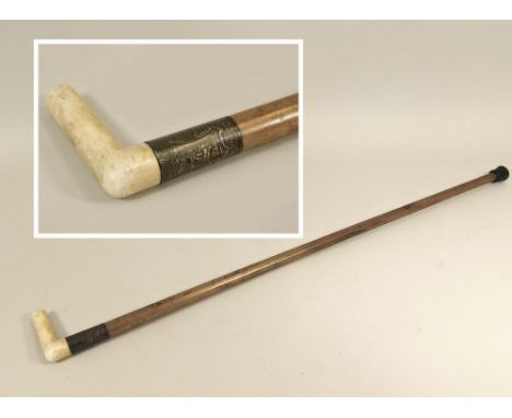 WALKING CANE. A walking cane with carved bone handle &amp; engine turned silver coloured metal collar.