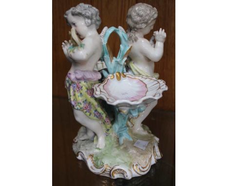 A Continental porcelain table centre piece, in the form of two putti, with scallop salts, factory mark to base, 20cm high