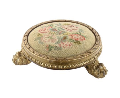A Georgian tapestry-topped footstool, with gilded wood surround and lion paw feet, diameter approx 46cmSome chips to paw feet