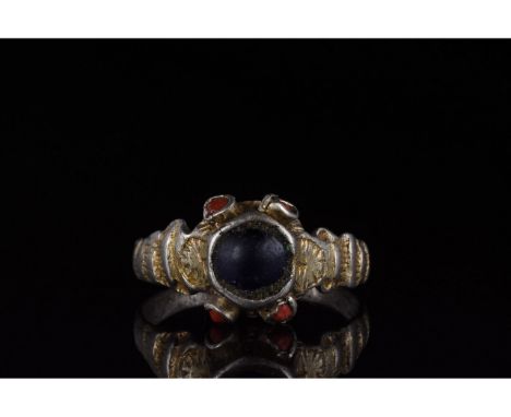 1100-1300 AD. Medieval. A silver gilt ring with a circular hoop scalloped shoulders and trumpet bezel comprising a large blac