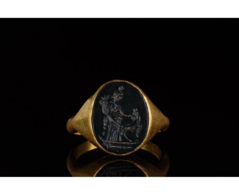 100-300 AD. Roman. A gold ring with a circular hoop and elliptical bezel with a black hardstone depiction of Fortuna, holding