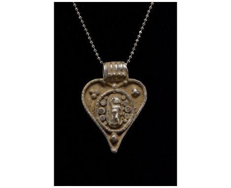 100-300 AD. Roman. A silver pendant in the shape of a heart with an applied strap suspension loop with ribbing. The plate is 