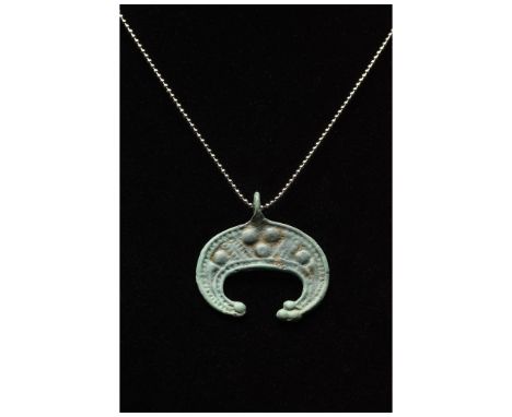 C. 900-1100 AD. Viking Period. Bronze lunar pendant a crescent moon with raised circular and geometric decorations and a smal