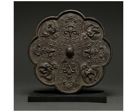 Ca. 700 AD. Tang Dynasty. Rossete shaped bronze mirror with an intricate relief depicting repeating flying birds and entertwi