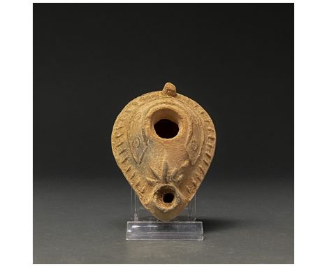 300-400 AD. Late Roman. A drop-shaped terracotta lamp with a snub spout and extensive geometric moulded decoration, as well a