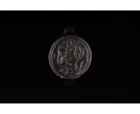 1100-1300 AD. Medieval. Bronze ring with D-shaped hoop and flattened, circular bezel featuring incised decoration depicting a