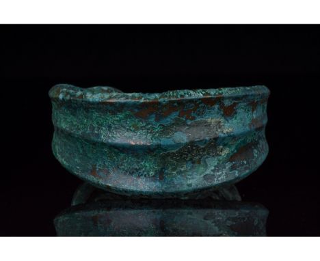 C. 1000â€“600 BC, Bronze Age. A heavy bronze bracelet with a flaring, ribbed midsection and coiled, spiral terminals. In the 