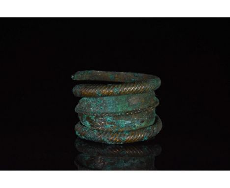 700-1100 AD, Viking Age. A bronze coiled ring with ttwisted railing ends and lozenge-shaped central plate bearing a line of a