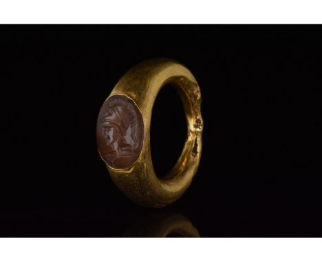 100-300 AD. Roman. Elaborate gold ring with circular hoop, flaring shoulders and elliptical bezel; an oval-shaped red gem set