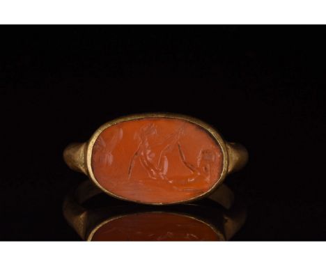 100-300 AD, Roman. A rare gold ring with a circular hoop and elliptical trumpet bezel with red gemstone intaglio bearing an e