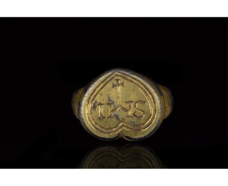1100-1300 AD. Medieval. A silver gilt ring with a round hoop and heart-shaped plate bezel bearing an double concentric heart 
