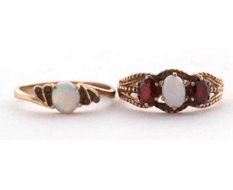 A 9ct opal and garnet ring, the oval opal cabochon with an oval garnet to either side, with split shoulders and plain band st