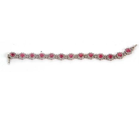 A ruby and white topaz bracelet, comprised of 15 clusters of round rubies surrounded by small round white topaz, each cluster