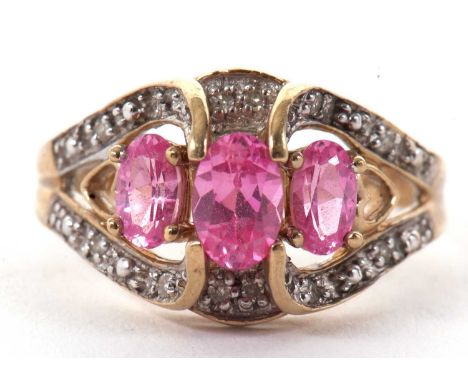 A 9ct pink gemstone and diamond ring, the three oval pink gemstones, claw mounted with shaped diamond set shoulders and taper