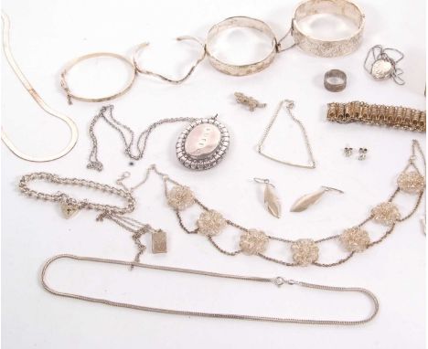 A quantity of silver and white metal jewellery to include three hinged silver bangles, an open ended bangle, a large oval sil