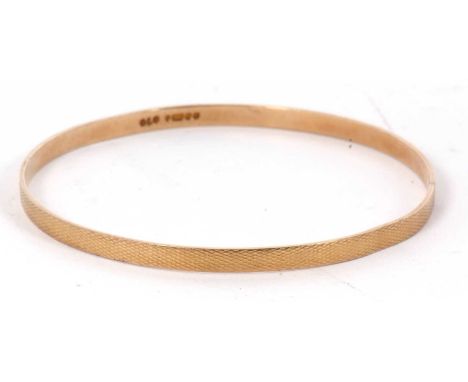 A 9ct upper arm gold bangle, the 4.5mm wide bangle with engine turned decoration, hallmarked Birmingham 1926, 7.5cm diameter,