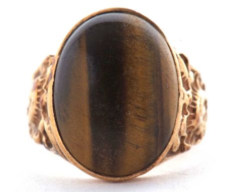 A 9ct tigers eye ring, the oval tigers eye cabochon, collet mounted to tapered textured shoulders and plain band stamped 9ct,