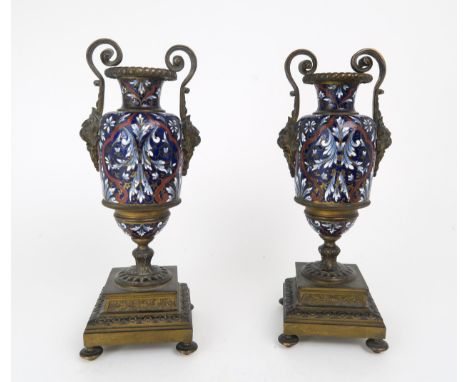 A PAIR OF FRENCH CHAMPLEVE ENAMEL AND GILDED METAL GARNITURE URNS each with lions head scroll handles, the bodies in shades o