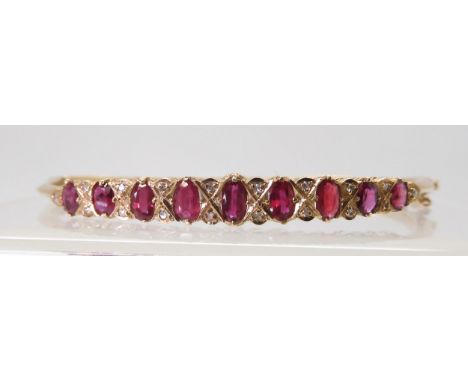 A 9CT RED GEM &amp; DIAMOND BANGLE with decorative galleried mount, inner diameter 6.2cm, weight 9.7gms Condition Report:Avai
