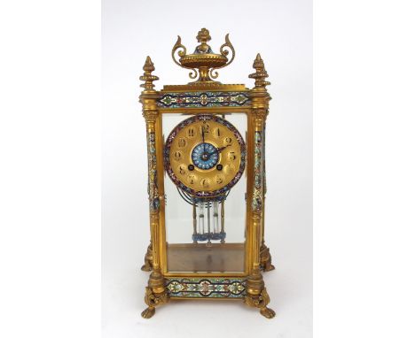 A FRENCH CHAMPLEVE ENAMEL AND GILT BRASS MANTEL CLOCK with four glass panels revealing the movement, the corners with four po