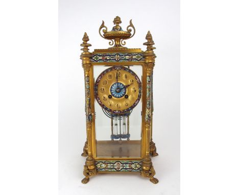 A FRENCH CHAMPLEVE ENAMEL AND GILT BRASS MANTEL CLOCK with four glass panels revealing the movement, the corners with four po