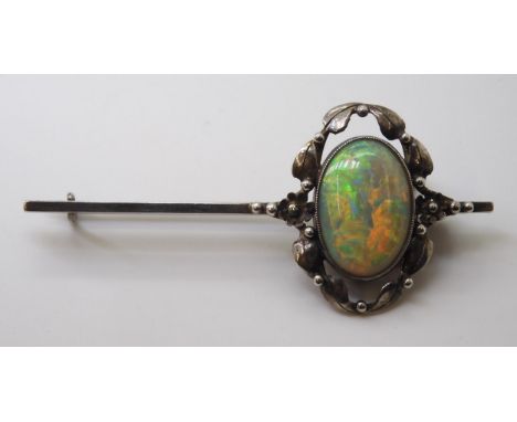 AN ARTS &amp; CRAFTS OPAL BROOCH set with a 16mm x 11.5mm solid opal with exceptional orange, red, green and blue colour play