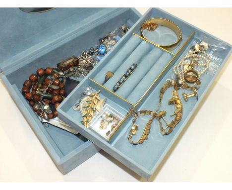 A gold plated hinged bangle, two charm bracelets and other costume jewellery in a modern jewellery box.