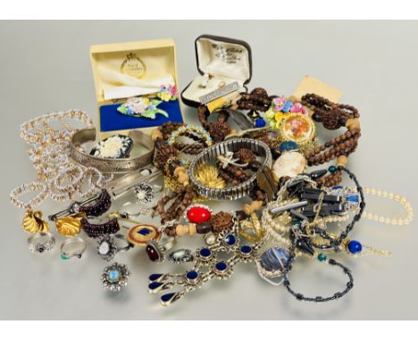 A collection of costume jewelry to include a carved bead necklace, gilt metal pendants and chains, brooches, collection of ri
