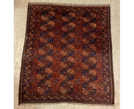 An Afghan Bokhara rug, first half of the 20th century, the red field with geometric motifs interspacing three rows of guls, f