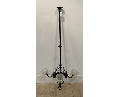 An early 20th century wrought iron electrolier ceiling light fitting, the column with pierced metal bracket having floral bos