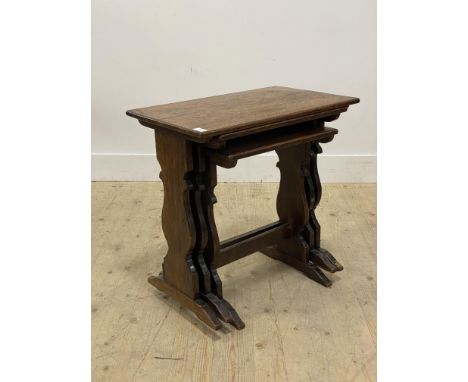 An early 20th century oak nest of three tables, each with rectangular top raised on shaped panel end supports. H60cm, W61cm, 