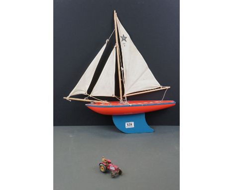 A wooden pond yacht together with a vintage toy tractor. 