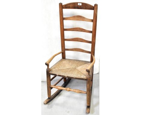 A 19th century oak provincial Lancashire ladder back rocking chair, with rush seat, double side stretchers and turned front s