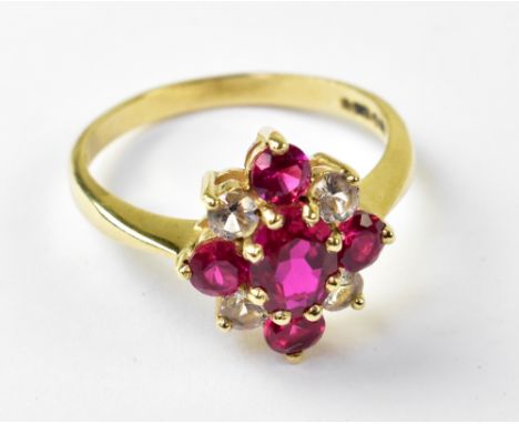 A ruby and white stone cluster ring with central claw set ruby and smaller ruby to top, bottom and sides in a cross formation