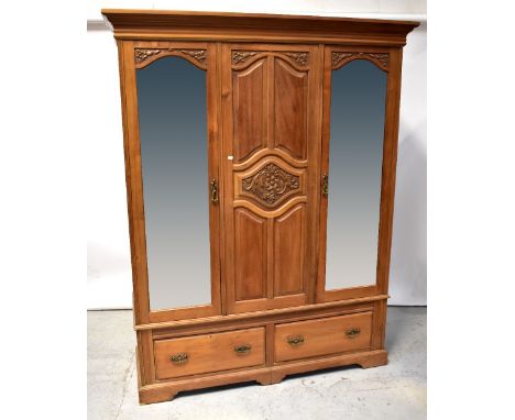 An Edwardian satin walnut triple wardrobe with moulded cornice above carved central panel, within four fielded panels flanked