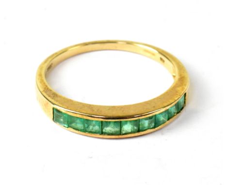 A 10ct yellow gold ring with a band set with ten baguette cut emeralds, size R, approx 2.2g.