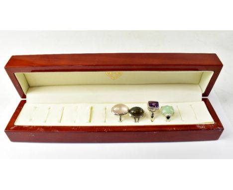 A wooden ring box with four silver ladies' dress rings, set with various stones to include rose quartz, amethyst, jade, vario