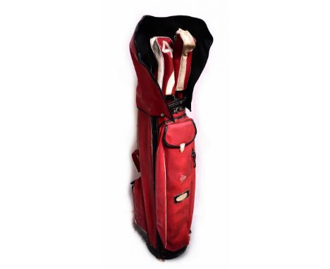 A vintage red golf bag containing a quantity of John Letters golf clubs.